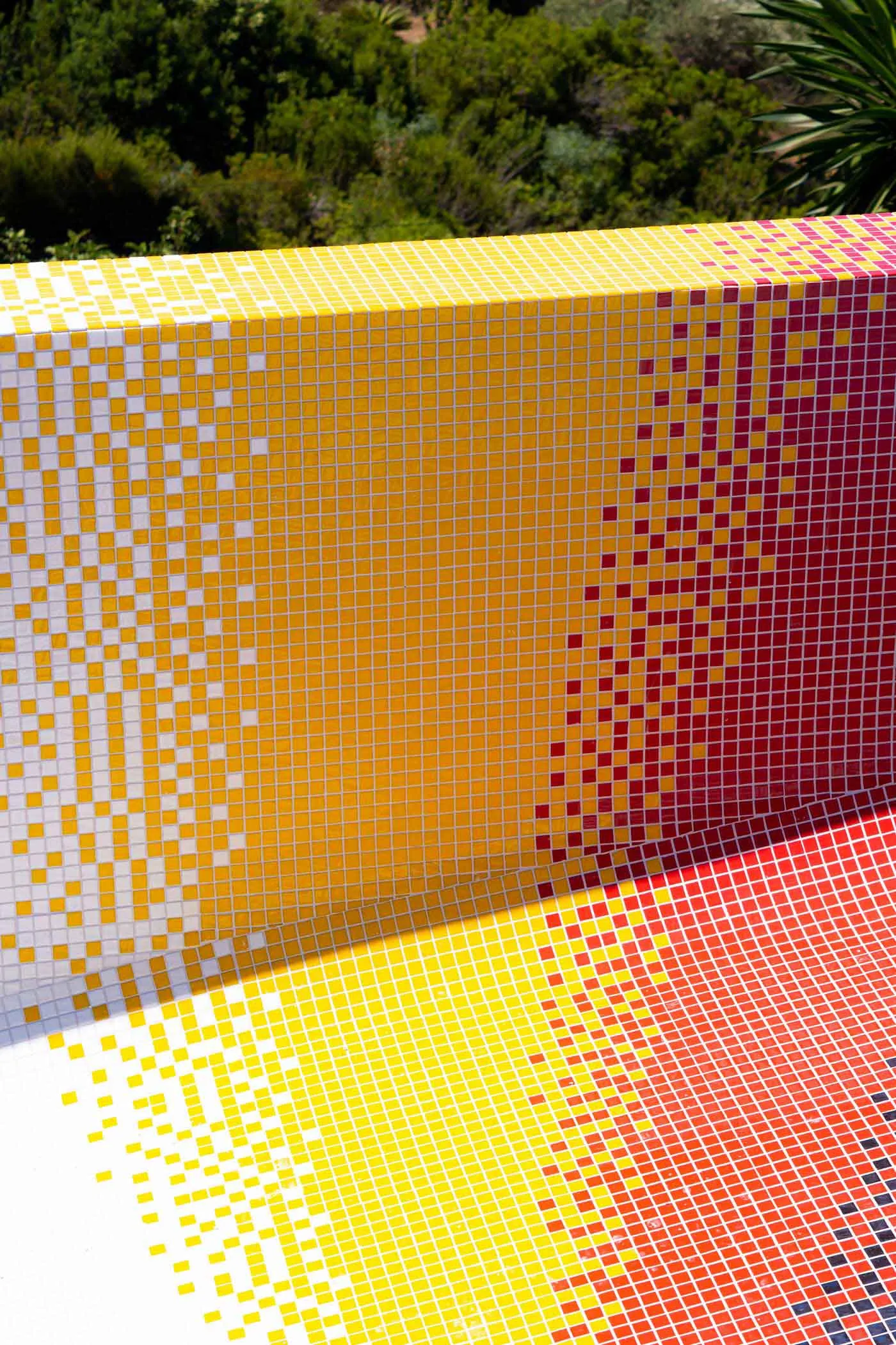 A modern swimming pool interior with a vibrant yellow, red, and white mosaic tile design.