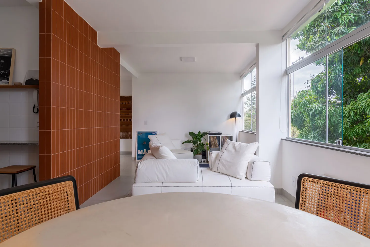 A modern living room with a white zippered-upholstered sofa, a window, and a lamp.