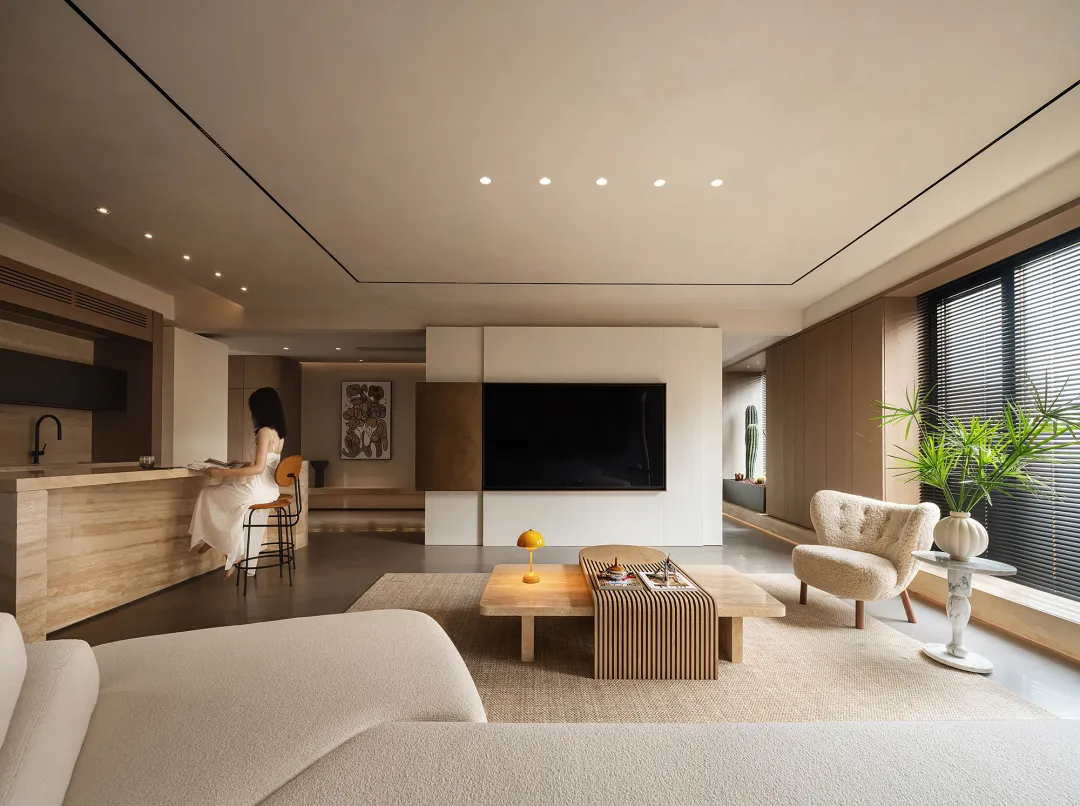 A modern minimalist living room featuring a large marble coffee table, wooden furniture, and fabric seating.
