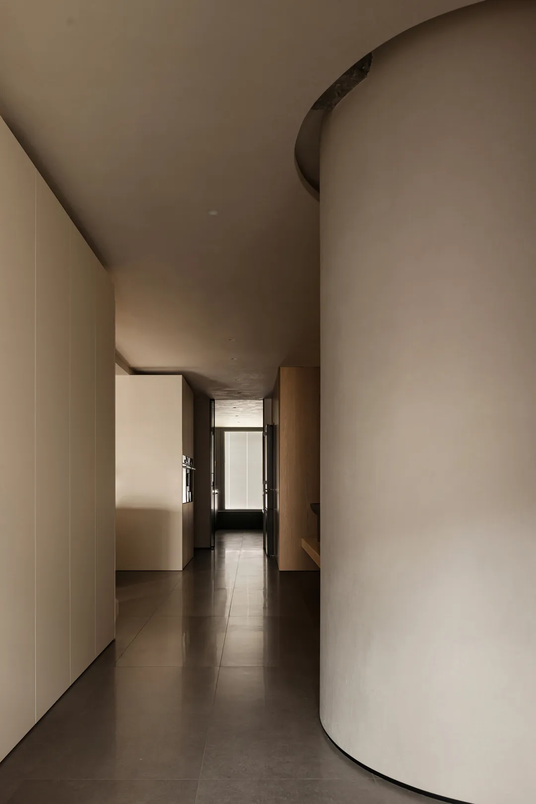 A minimalist interior with concrete walls, dark tiled flooring, and a curved pillar.