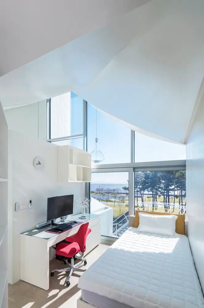 Modern bedroom featuring a window with a view of a landscape and a single bed.