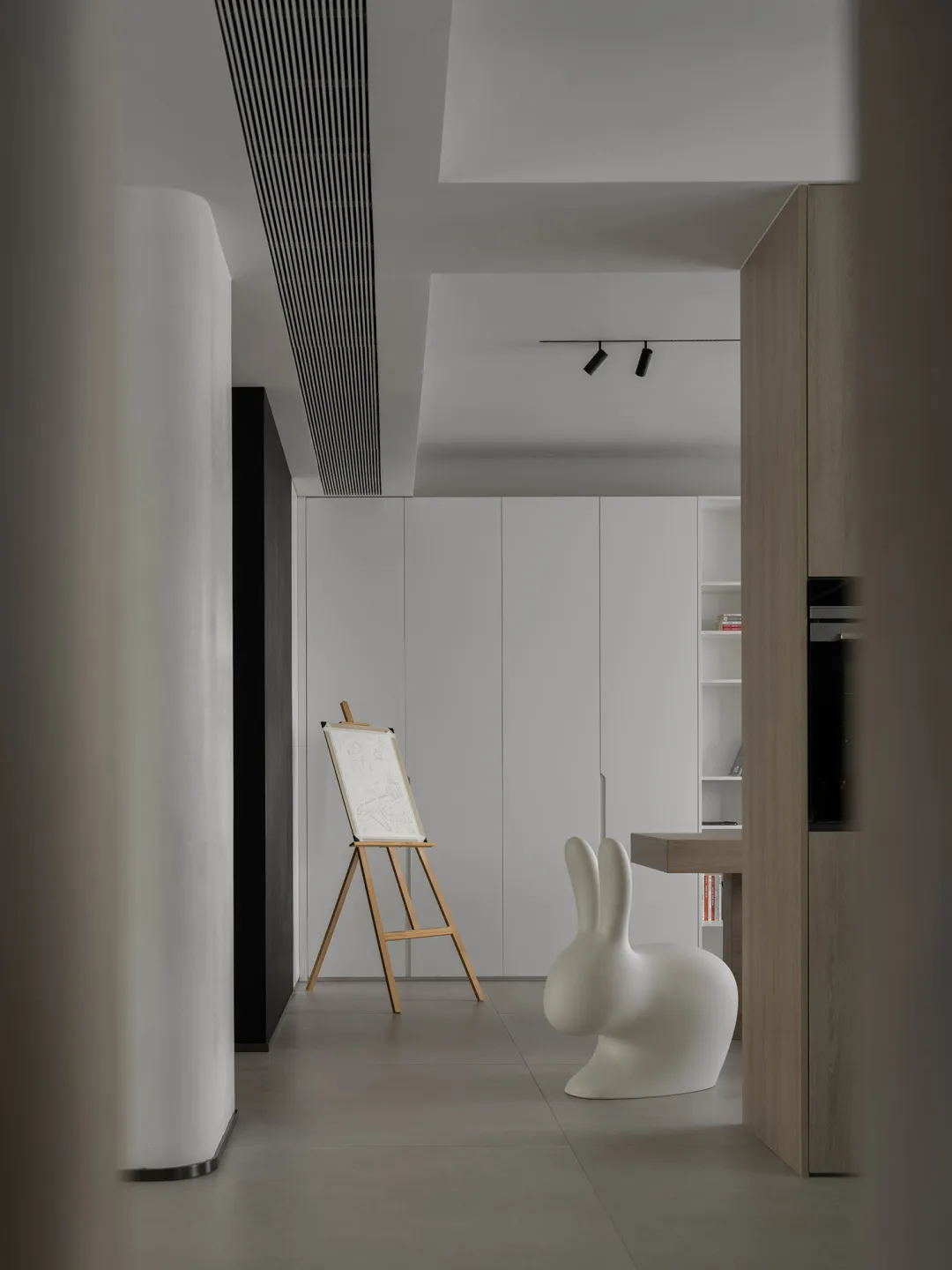 A minimalist art studio featuring a floating wooden table and white panels