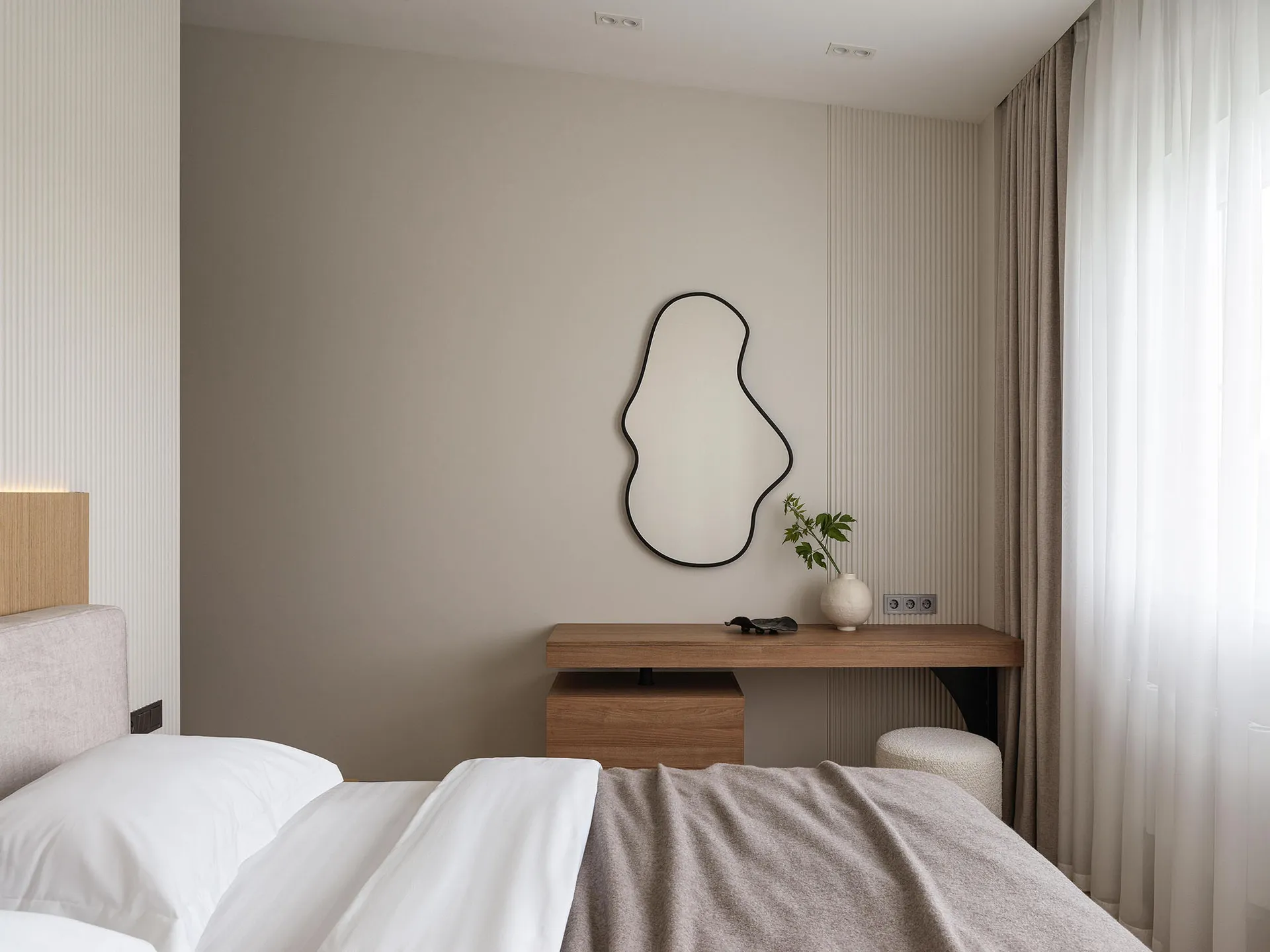 A minimalist bedroom with neutral tones and simple, modern furniture.