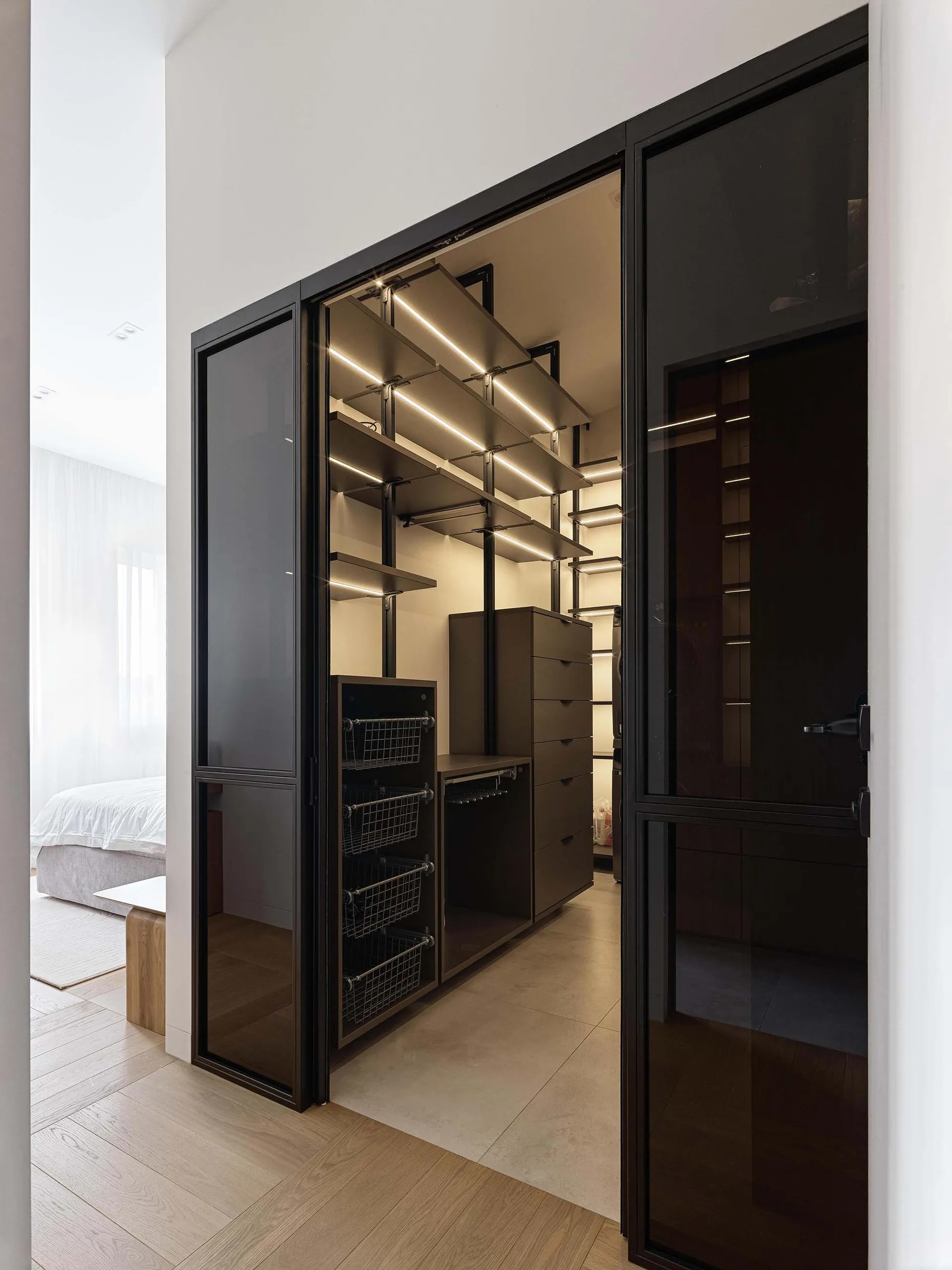 現代極簡衣櫃,配有金屬、玻璃與木質製成的層板、抽屜與收納籃。