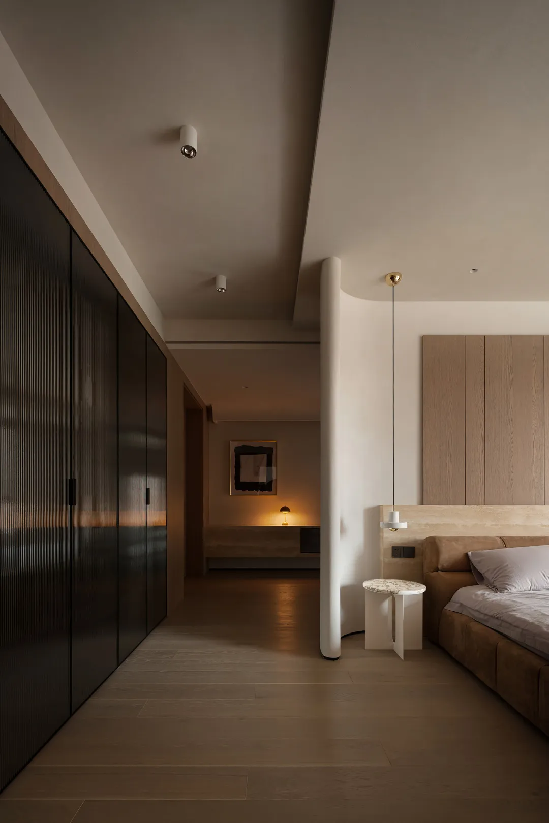 Modern bedroom featuring wooden flooring, sleek black wardrobe, and minimalist design elements.