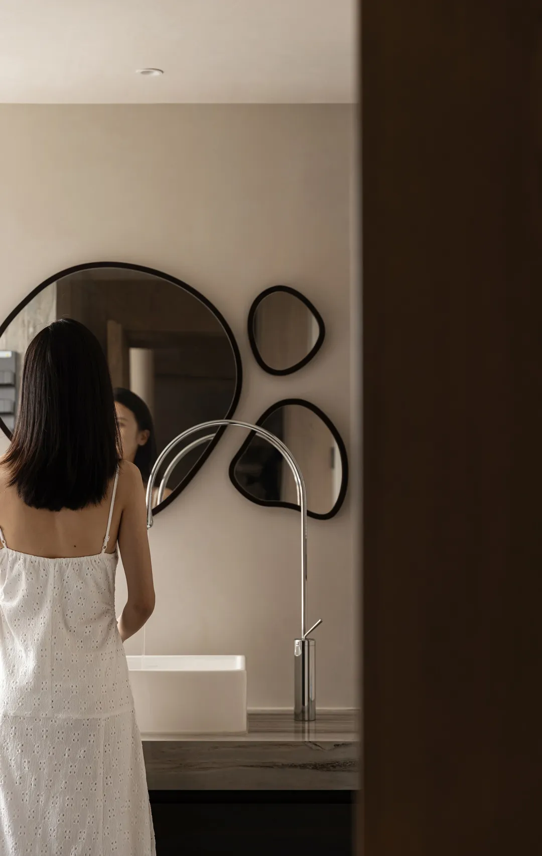 A minimalist bathroom with a ceramic sink, stainless-steel faucet, and modern design elements.