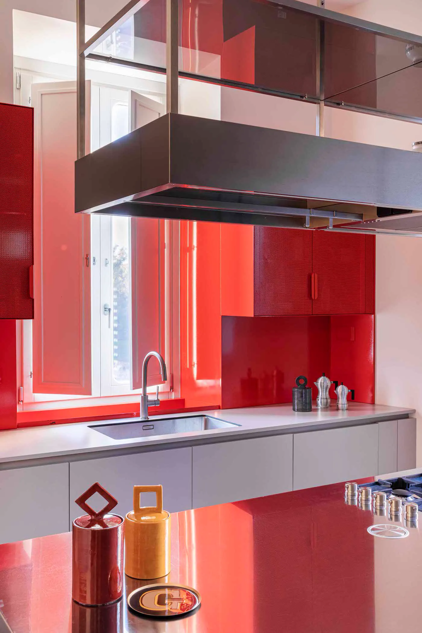 Modern minimalist kitchen featuring red cabinets and stainless steel appliances.