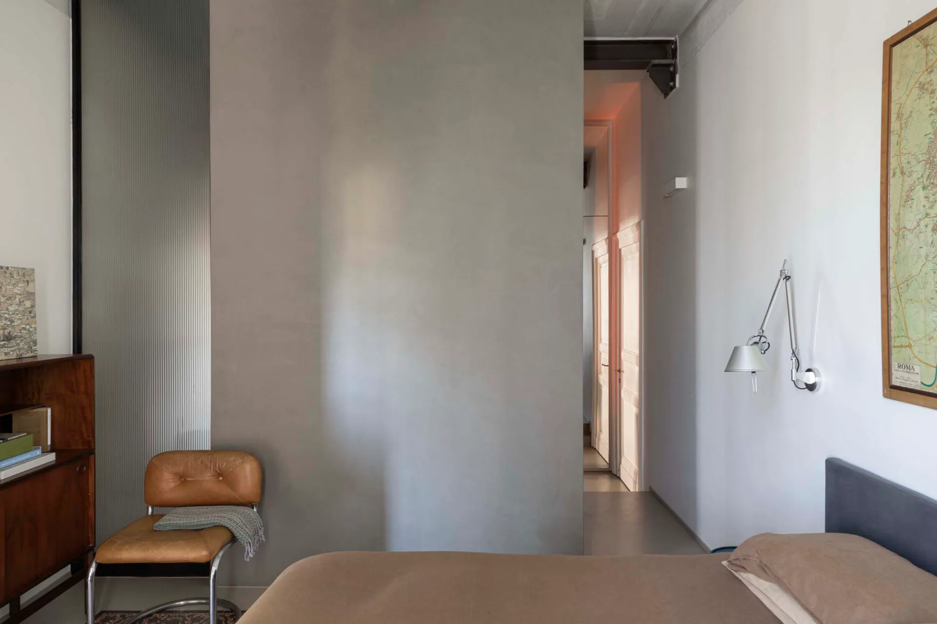Modern bedroom with metal wall lamp, minimalist style, concrete floor.
