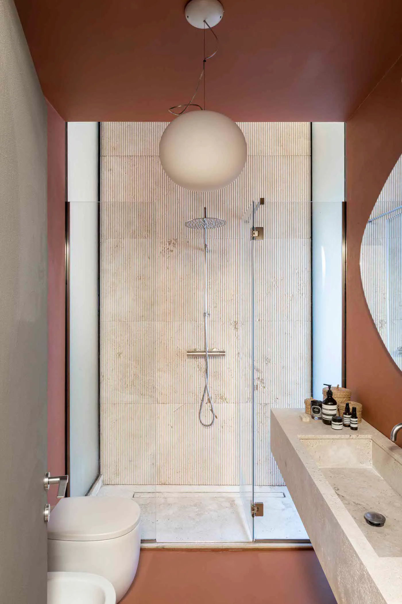 Modern bathroom with marble tiles and a spherical light fixture.