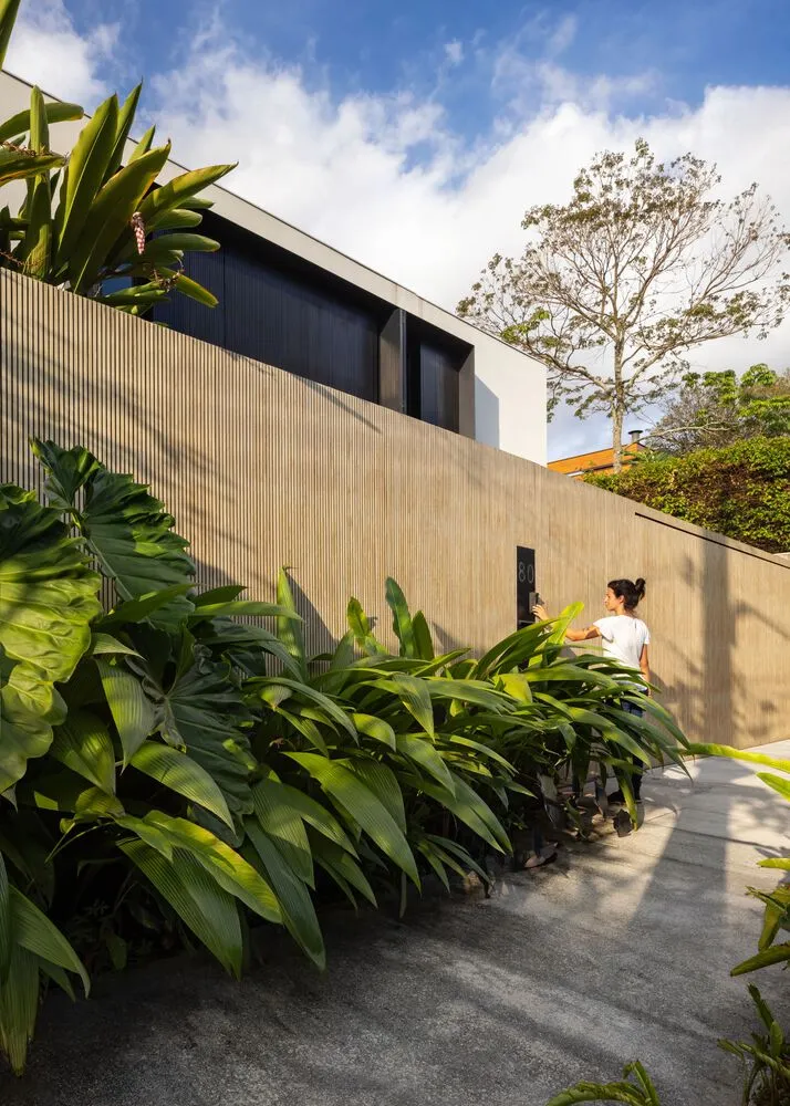 Modern house with wooden fence and lush greenery.