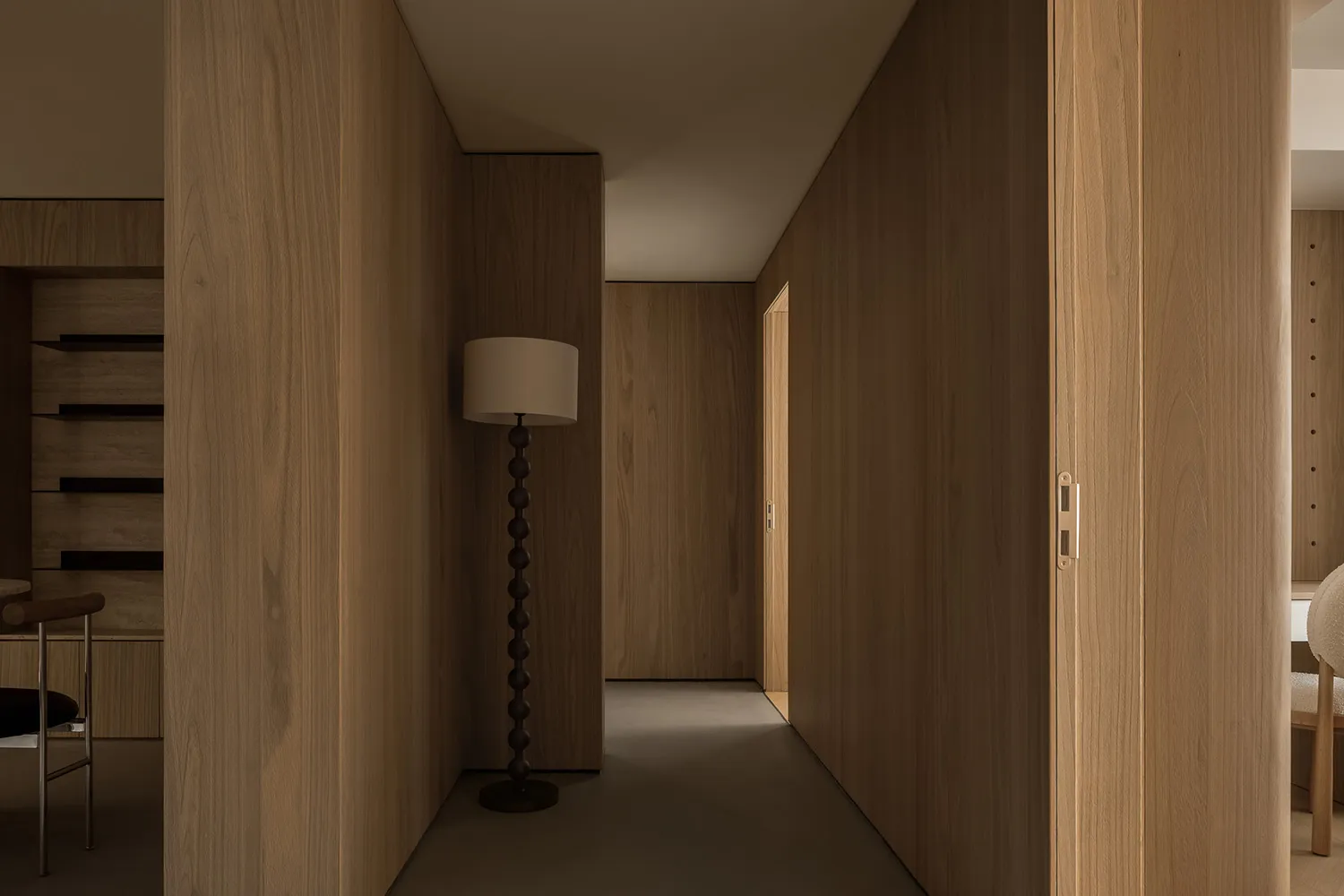 A minimalistic corridor with wooden walls and flooring, featuring a modern floor lamp.