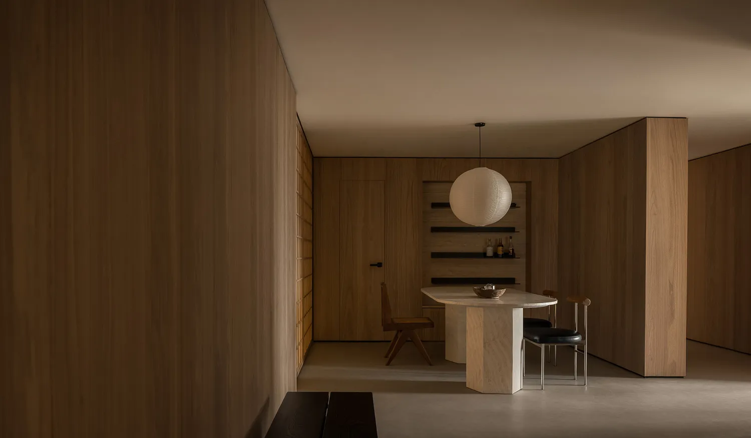 A minimalist dining room with wooden walls and furniture, featuring a round table with chairs.