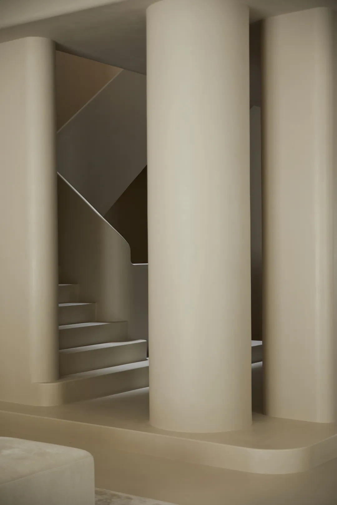 Modern, minimalist concrete staircase with sleek, cylindrical columns.