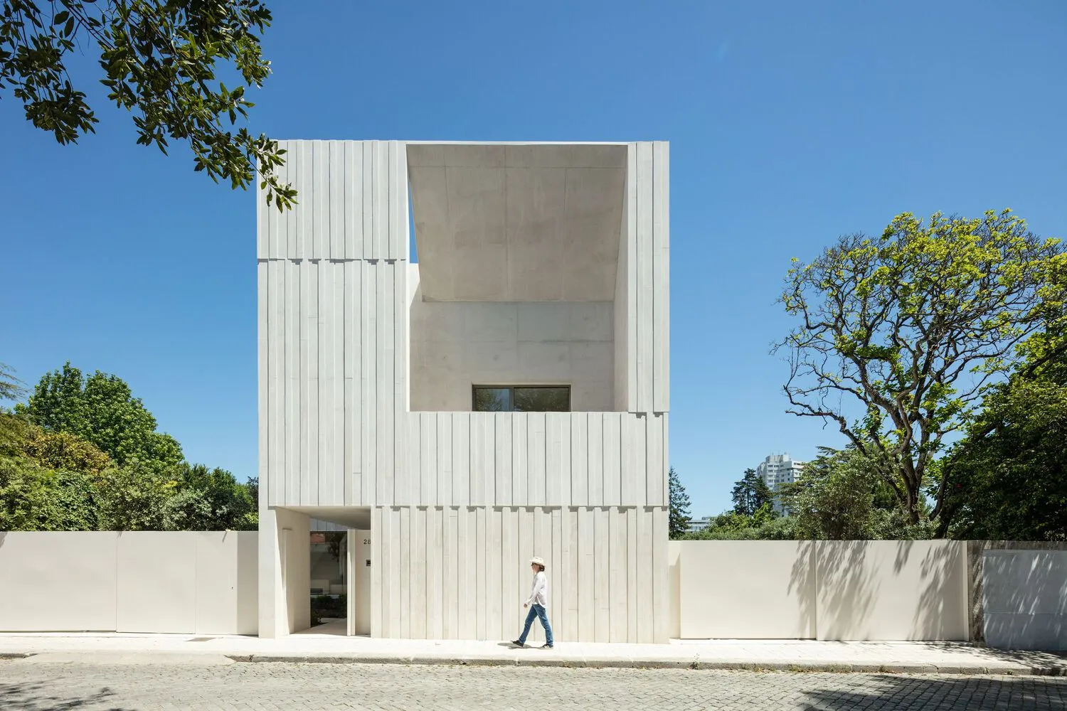 Modern residential building with a white, minimalist exterior made of concrete.