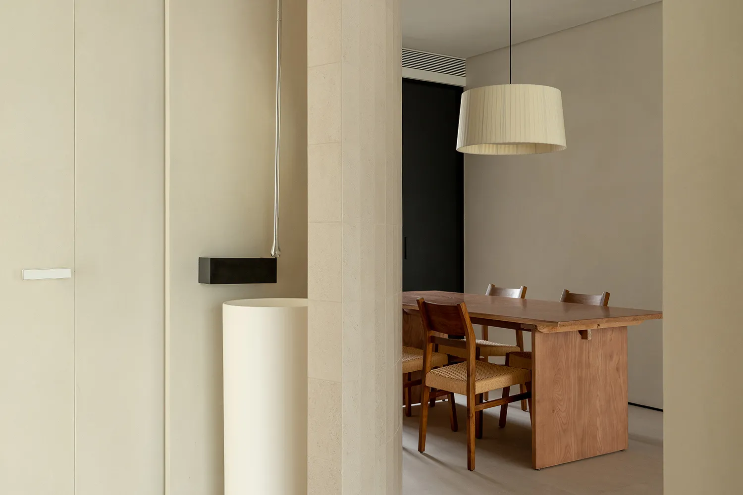 Modern minimalist dining room featuring a wooden table with woven fabric chairs.