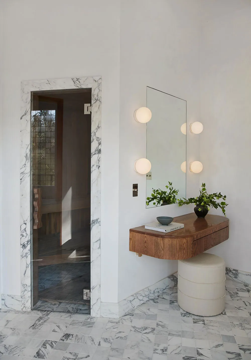 A minimalist interior featuring a marble entrance with a wooden vanity and round lights.