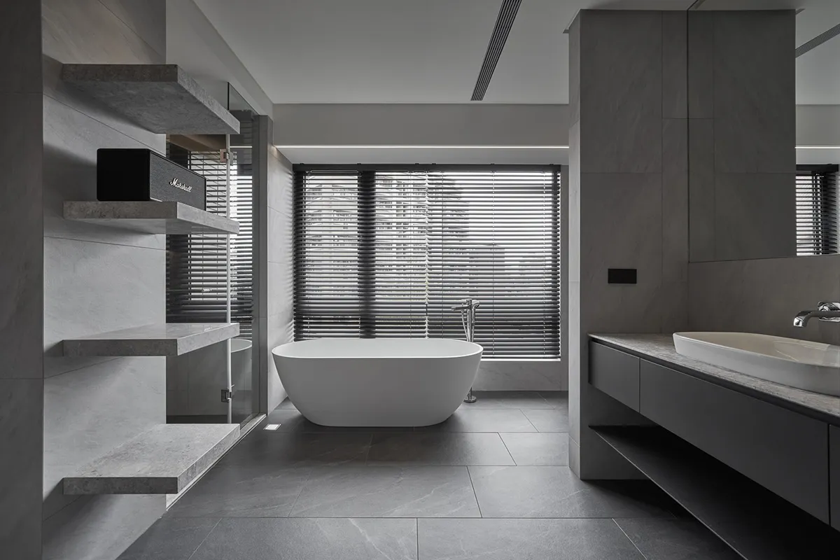 A modern bathroom with concrete flooring, a freestanding bathtub, and minimalist design.
