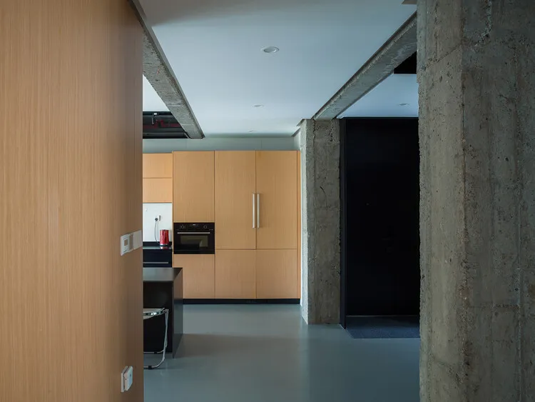 Modern kitchen interior with wooden cabinets and concrete accents.
