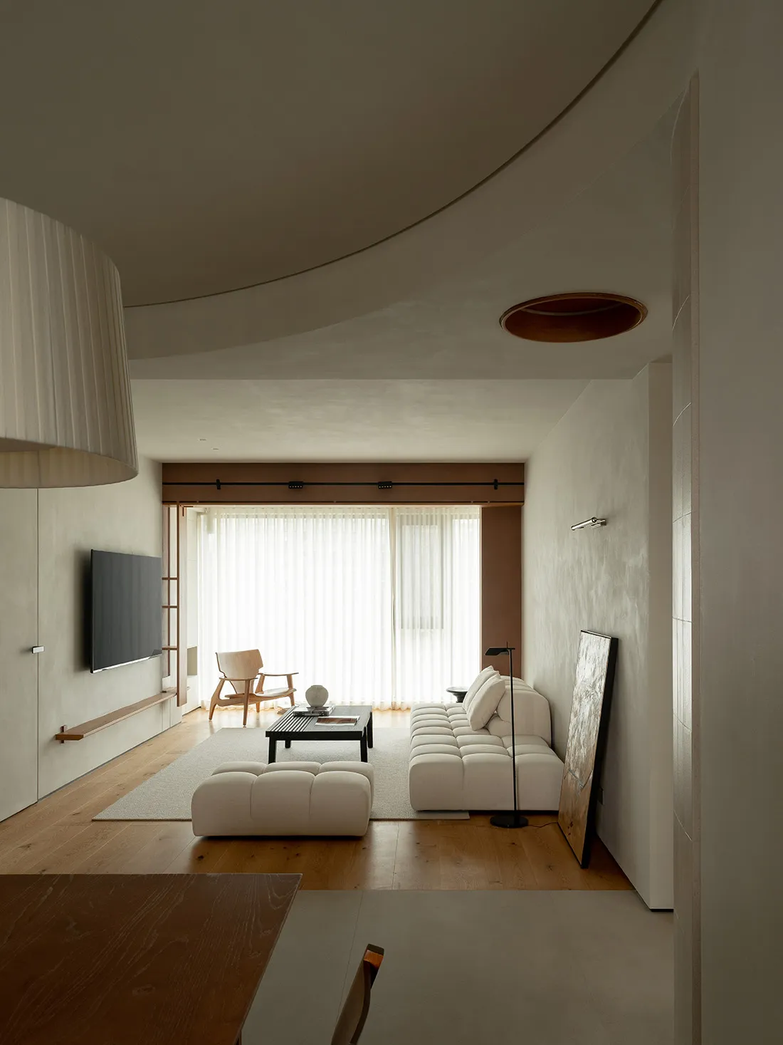 A modern living room featuring neutral-toned furniture and materials, with a minimalist design aesthetic.