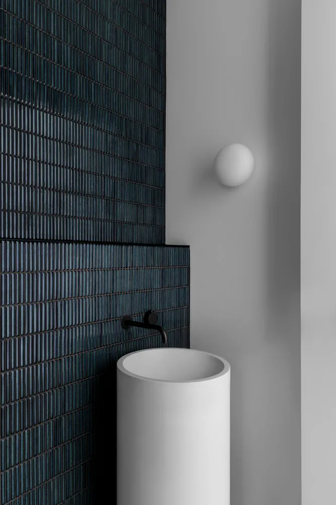 Modern industrial washroom with concrete walls and white pedestal sink with black faucet