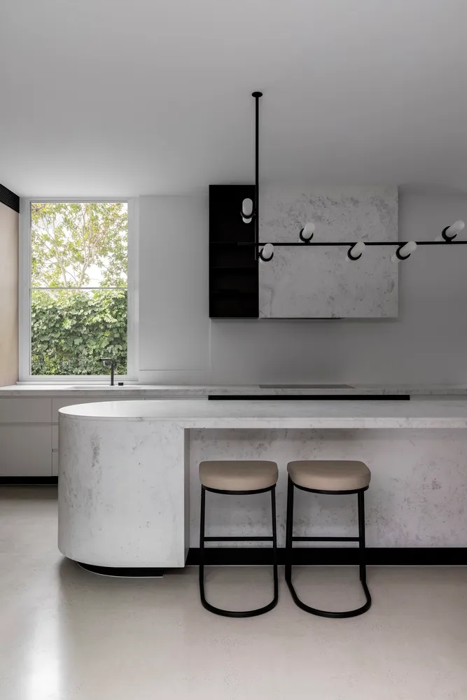 Modern, minimalist kitchen with marble countertop and stools.