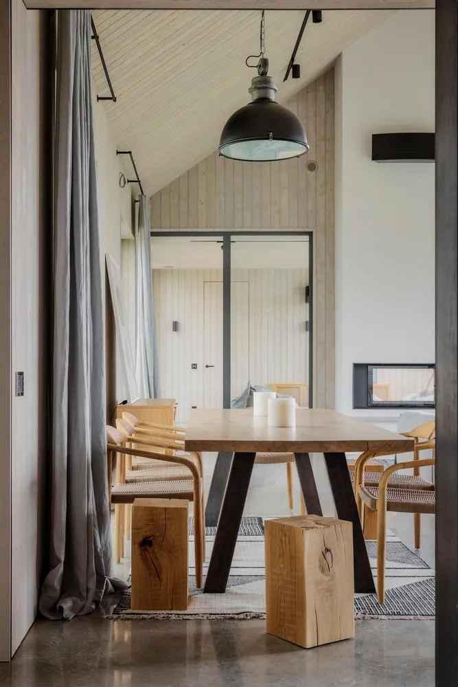 Modern and minimalist residential kitchen with wooden elements and a table.