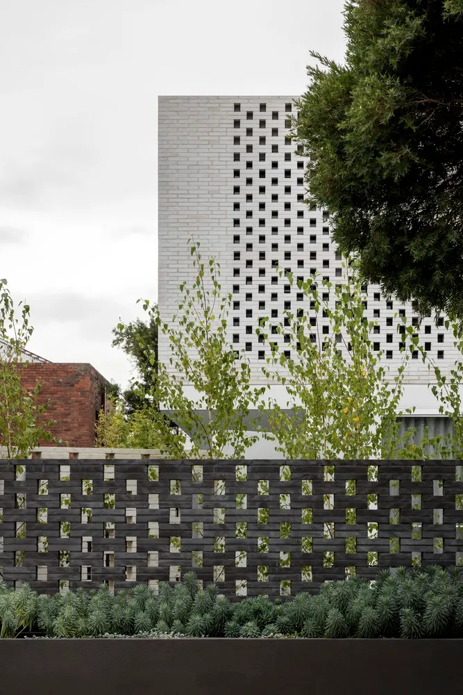 A modern building constructed with brick materials, featuring a grid-like pattern on the facade.