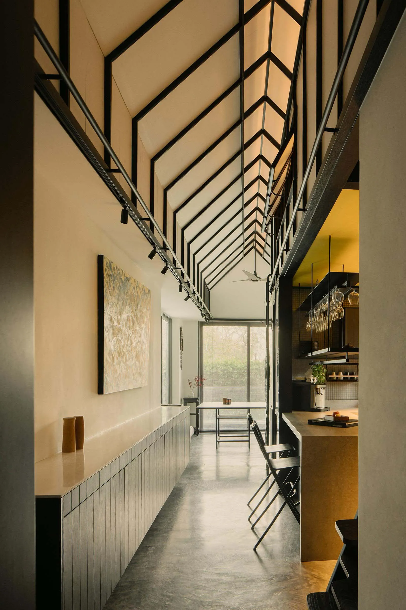 Modern residential entryway with concrete flooring, high ceiling, and industrial-style lighting.