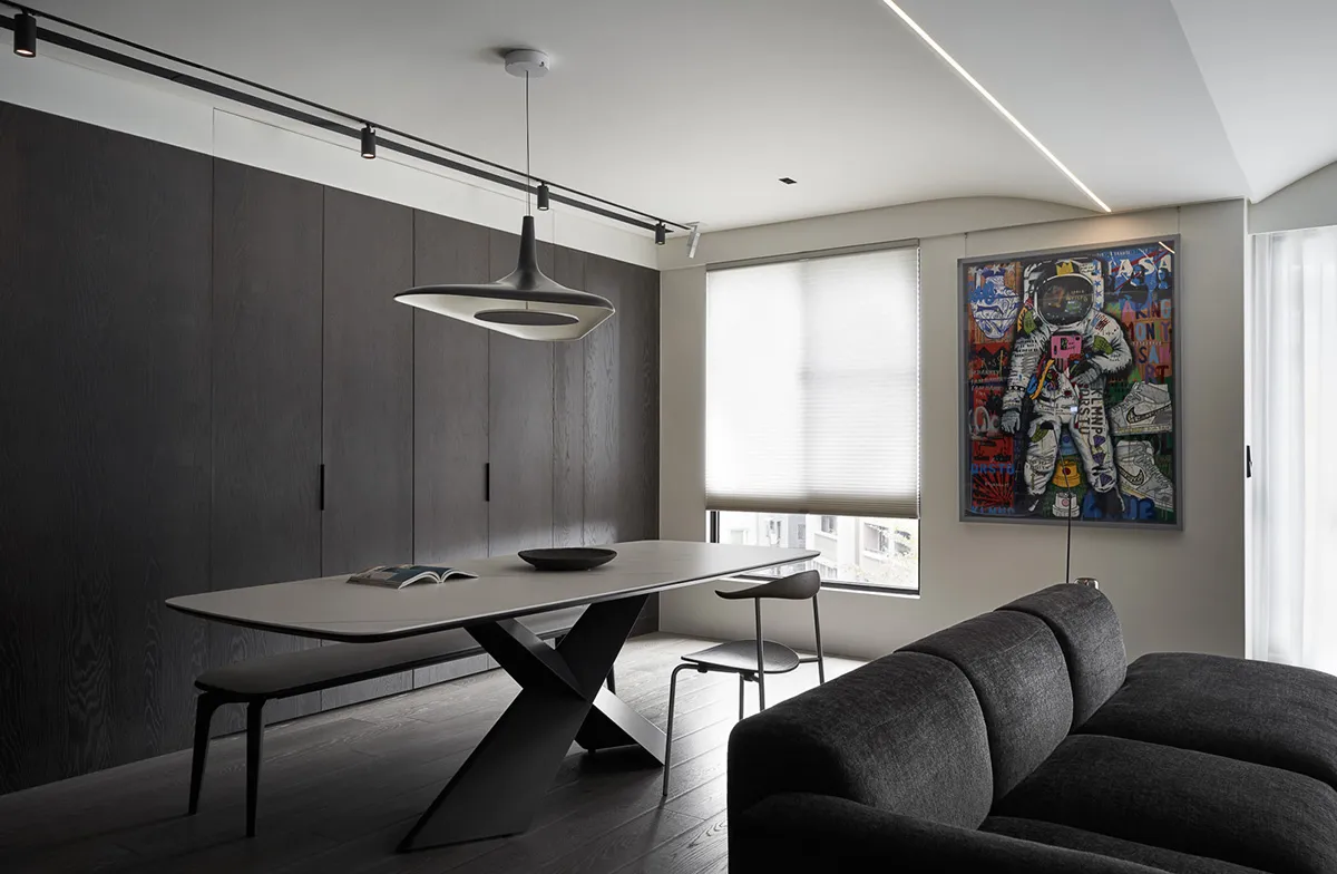 A modern living room featuring a minimalist design with dark wood flooring, glass table top, and metal furniture.