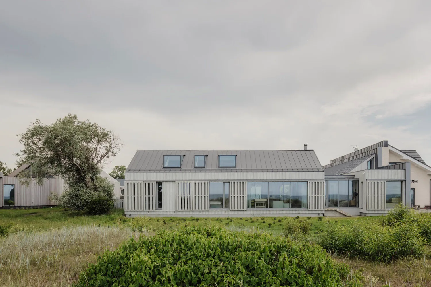 A modern metallic residential home with large windows and a flat roof.