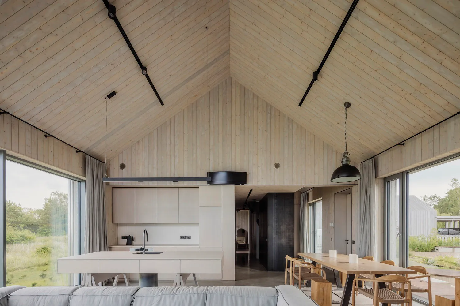 Modern, minimalist dining and kitchen area featuring wood finishes and open design.