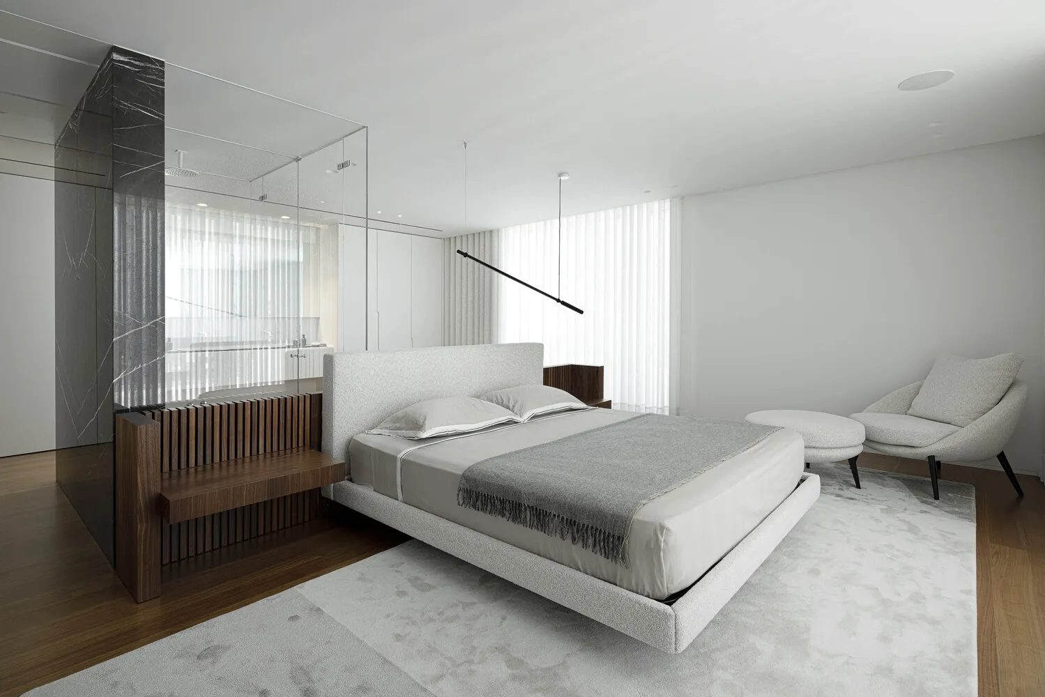 Modern minimalist bedroom with a wall-mounted marble accent piece and upholstered furniture.