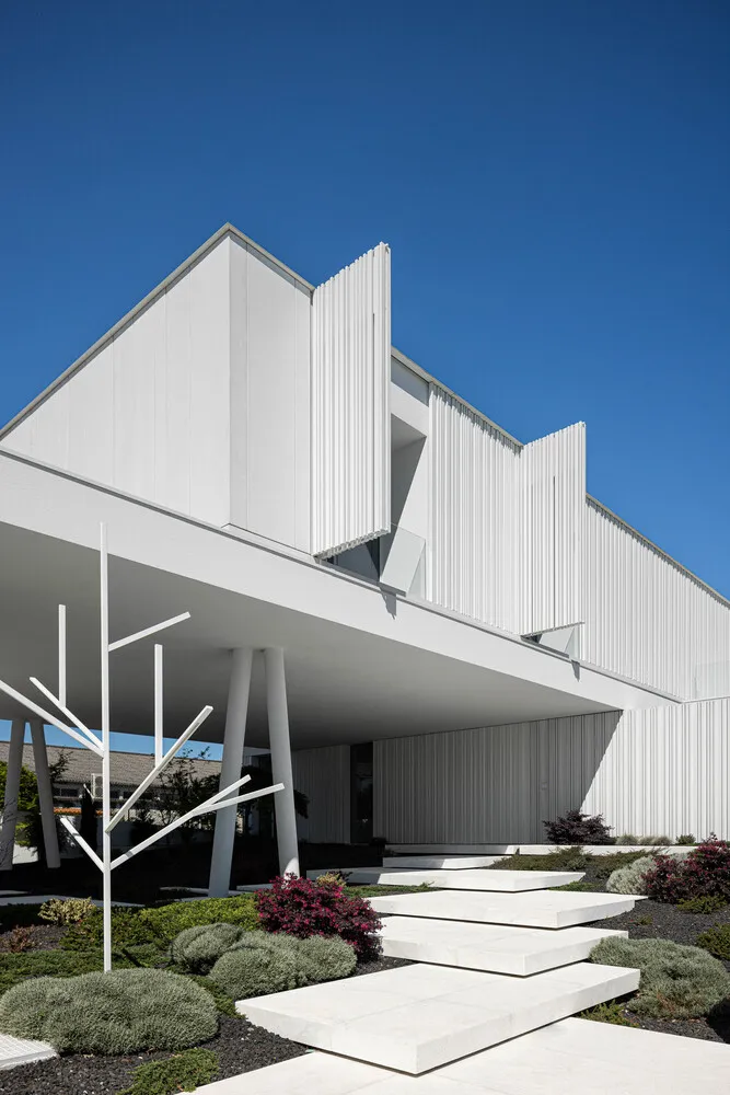 Modern building with white concrete architecture and greenery around it.