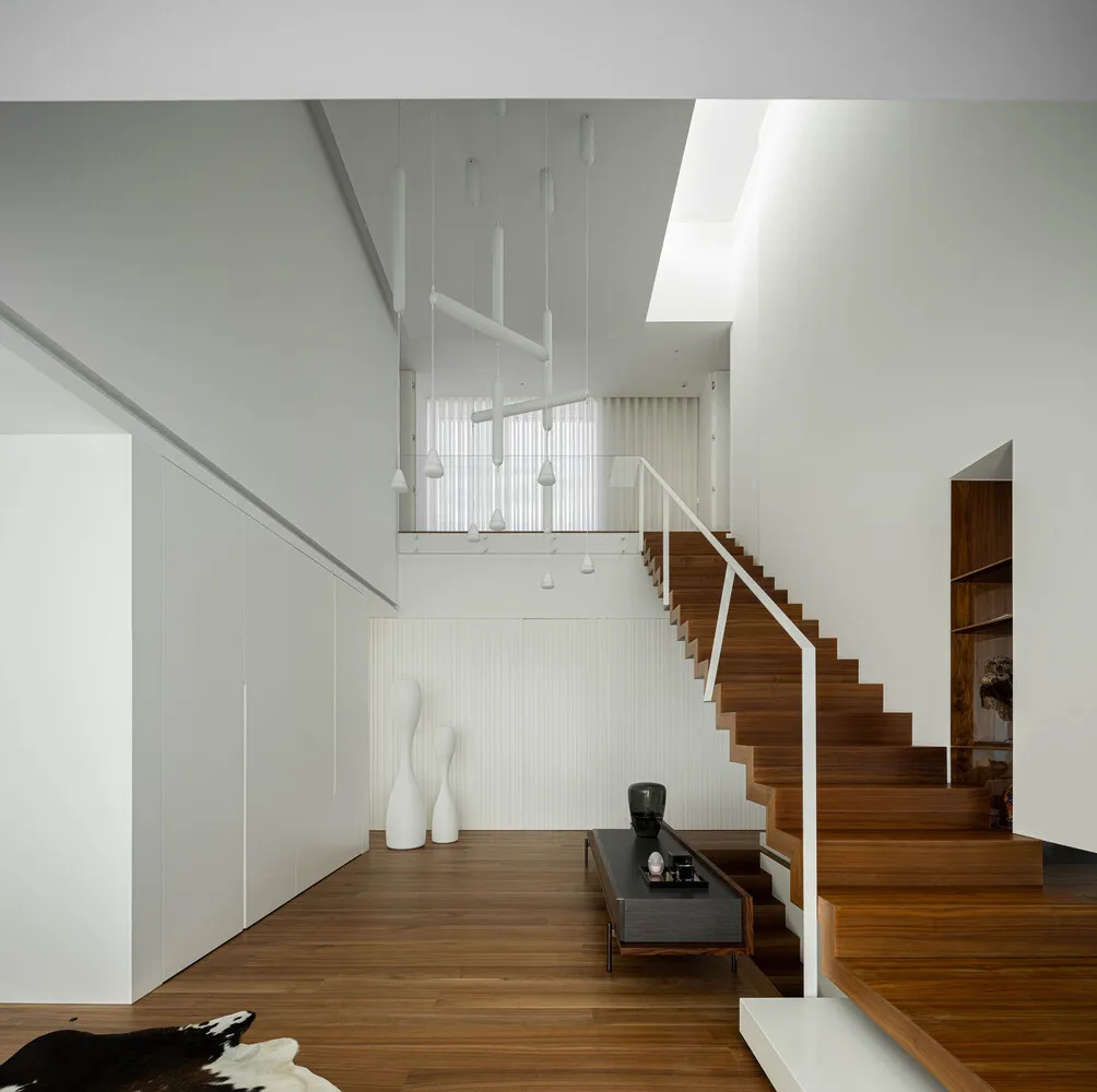 Staircase with wooden steps and white walls in a modern interior design.