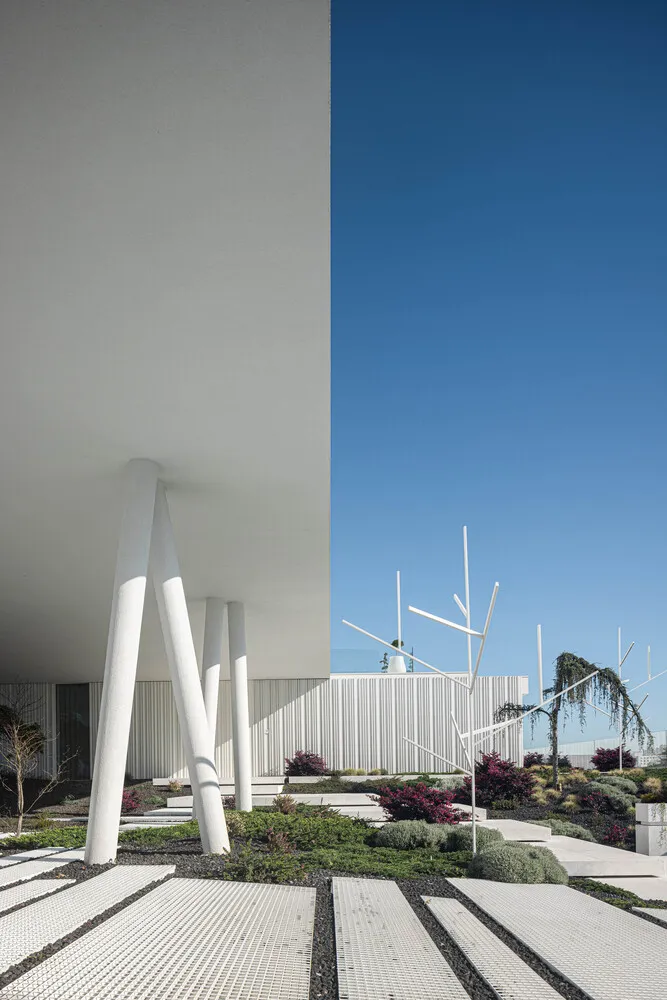 A minimalist building with concrete elements and a white structure.