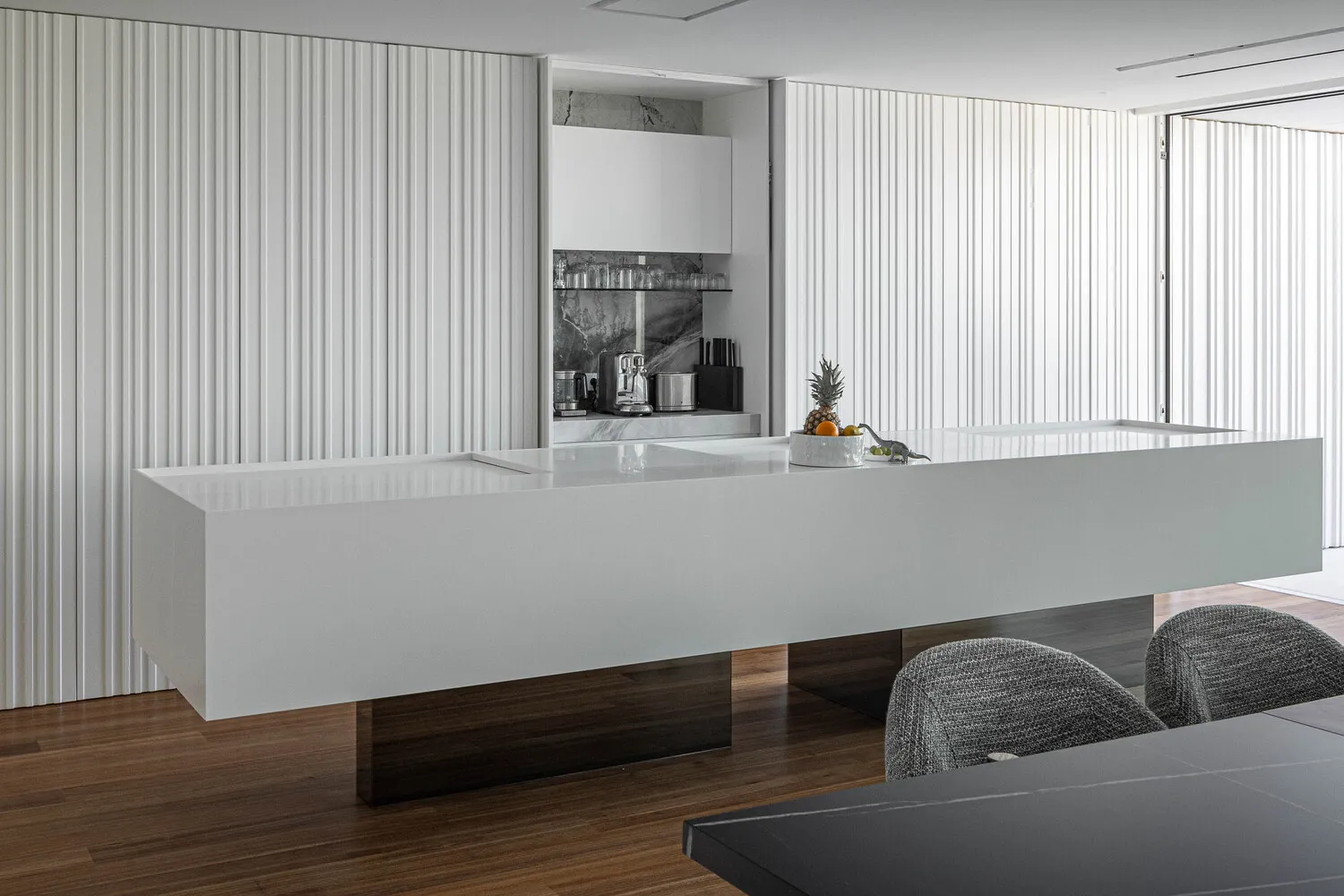 Modern minimalist kitchen featuring marble countertops and white vertical paneling.