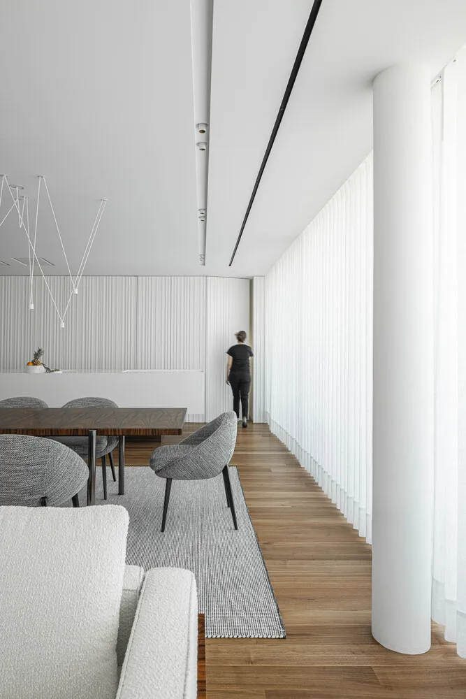 Modern minimalist living room with wood flooring, fabric furniture, and glass windows.