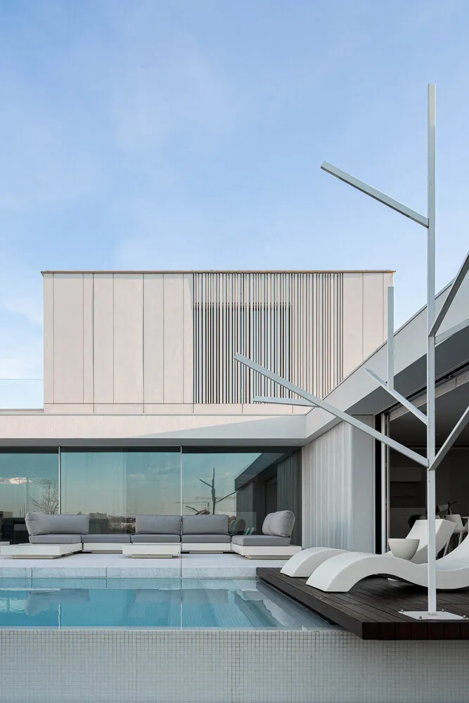 A modern residential pool deck featuring glass railings and contemporary furniture.
