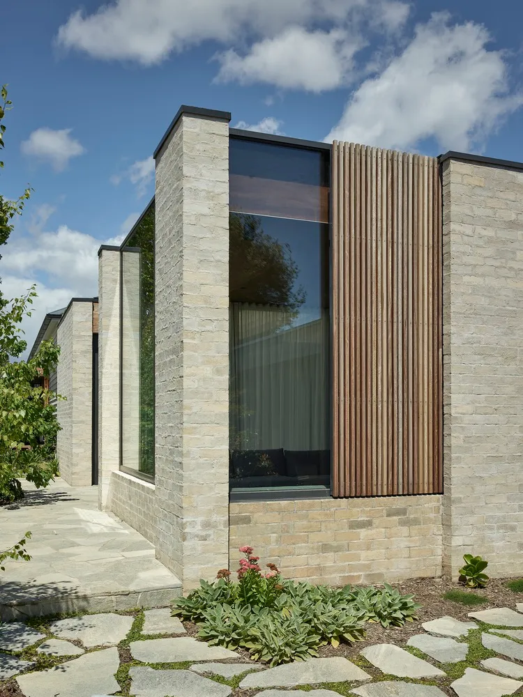 Modern house exterior featuring brick, glass, and wooden elements.