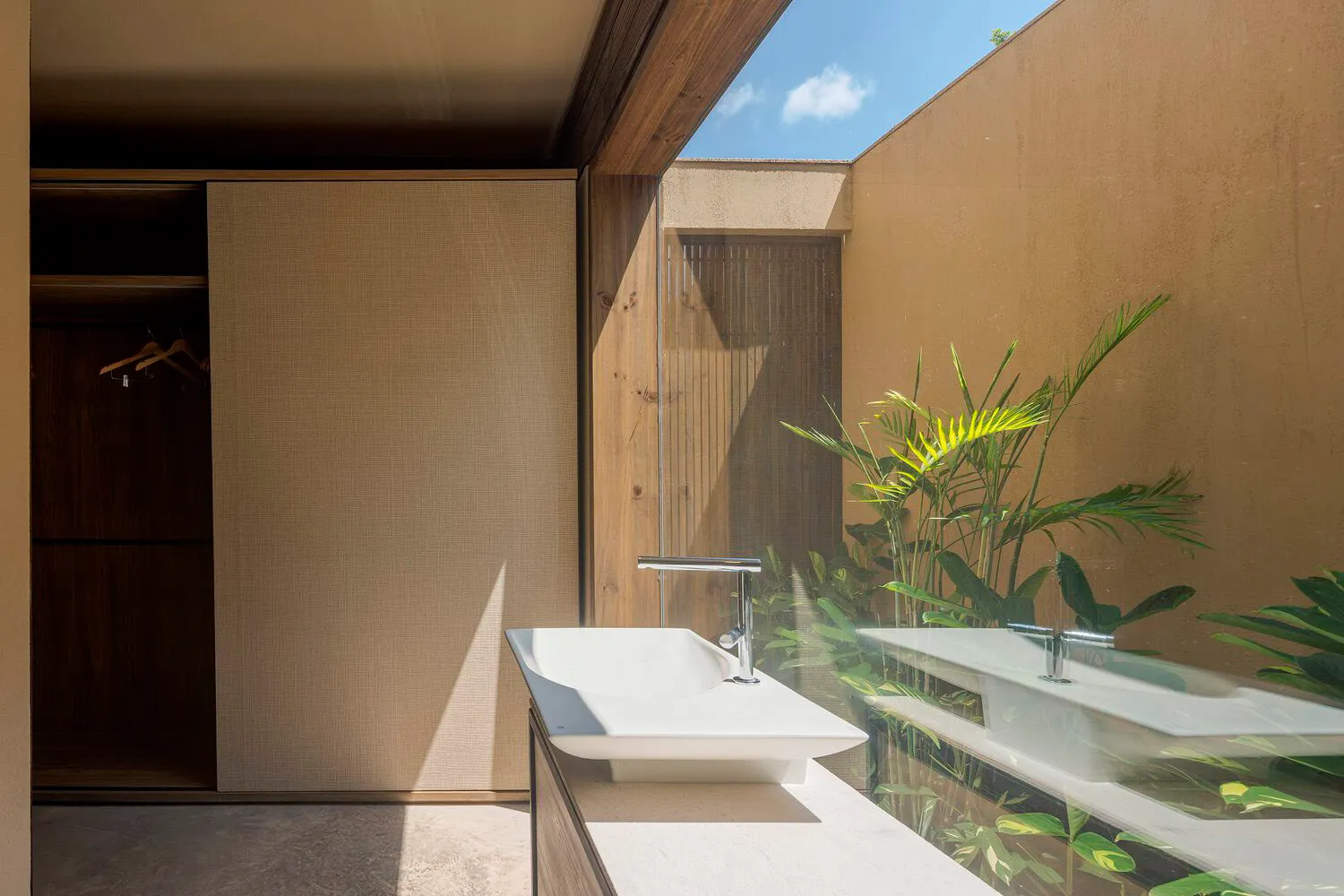 Modern bathroom with minimalist design featuring concrete materials and tropical plants.