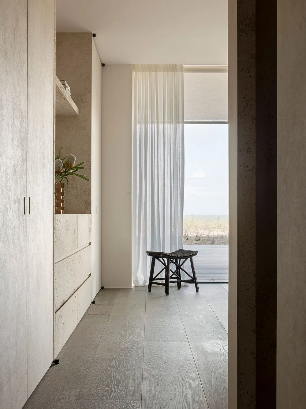 Modern interior design featuring wooden floor, white furniture, and sheer curtains.