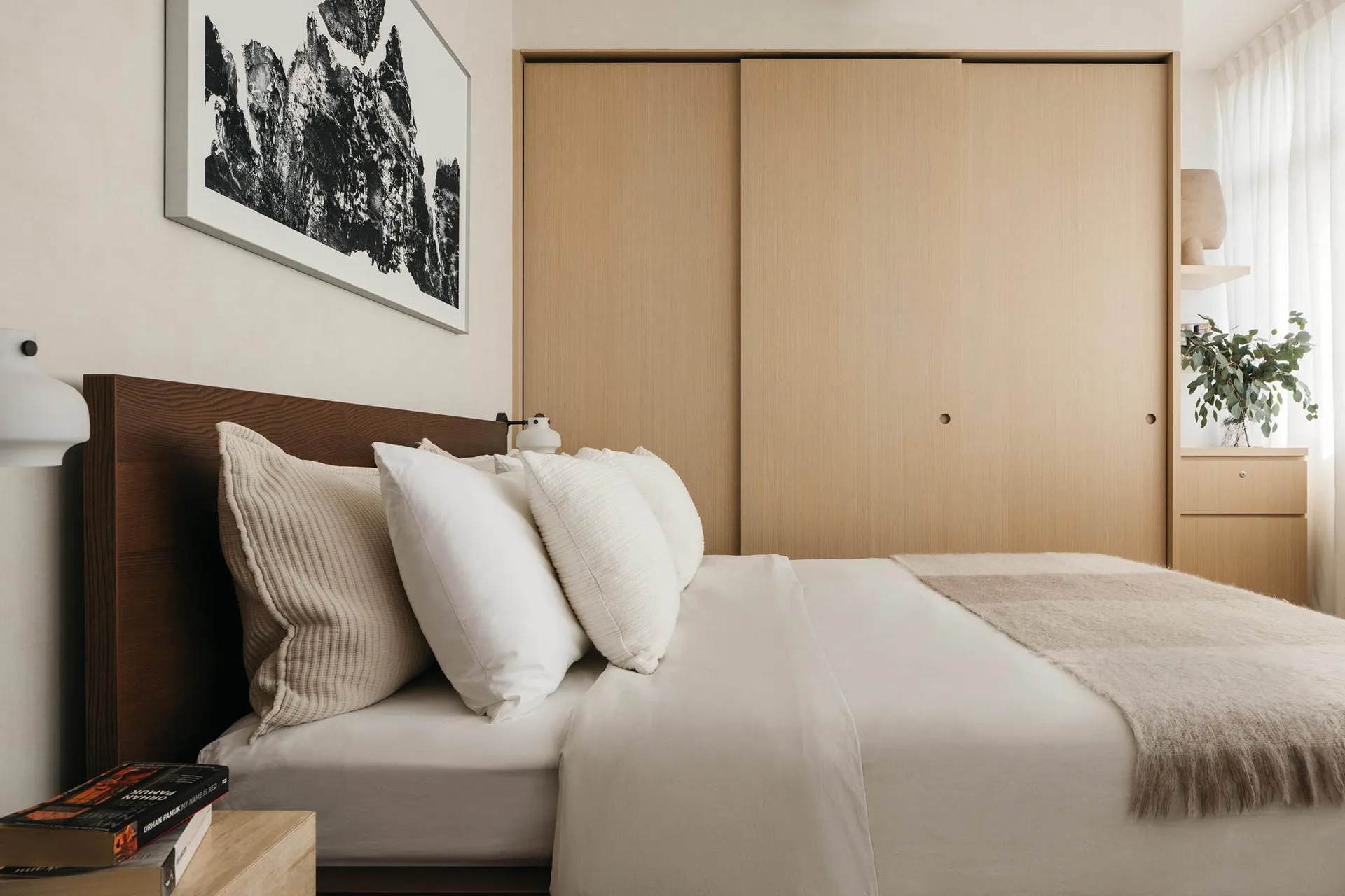Bedroom featuring a minimalist design with wooden furniture and a metal headboard.
