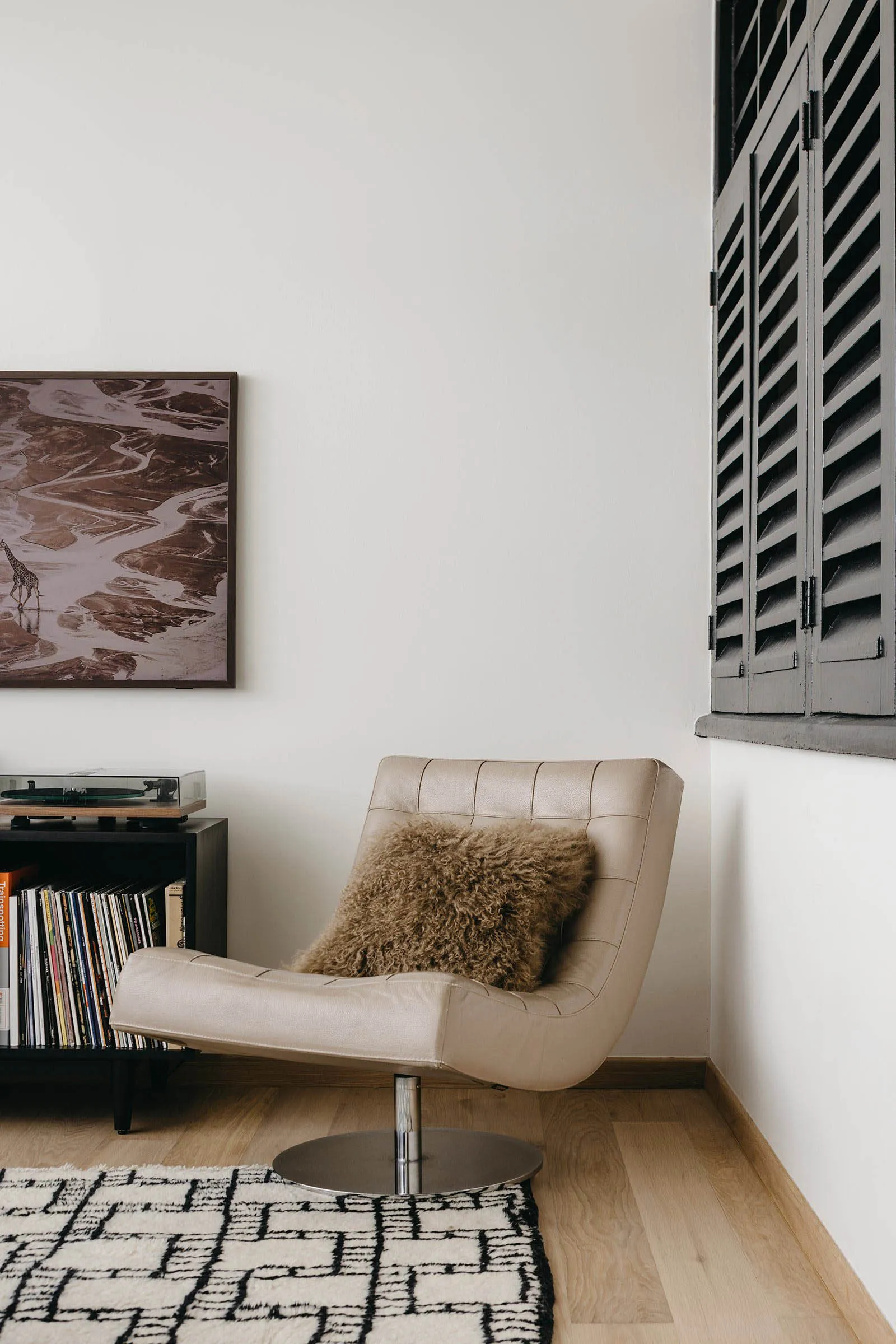 A modern leather chair with a fluffy pillow in a room with white walls and a wooden floor.
