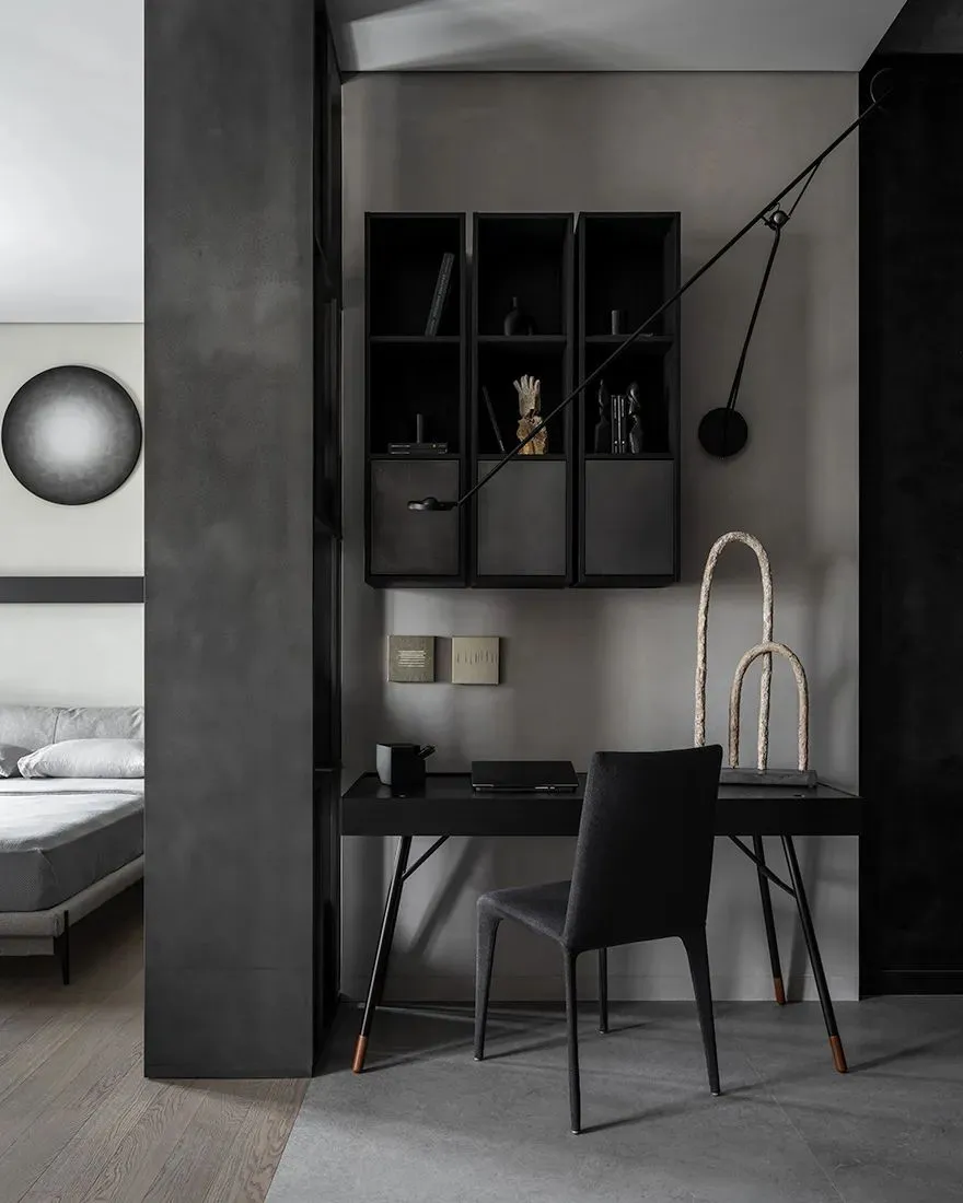 A minimalist office space featuring metal furniture, concrete walls, and wooden flooring.
