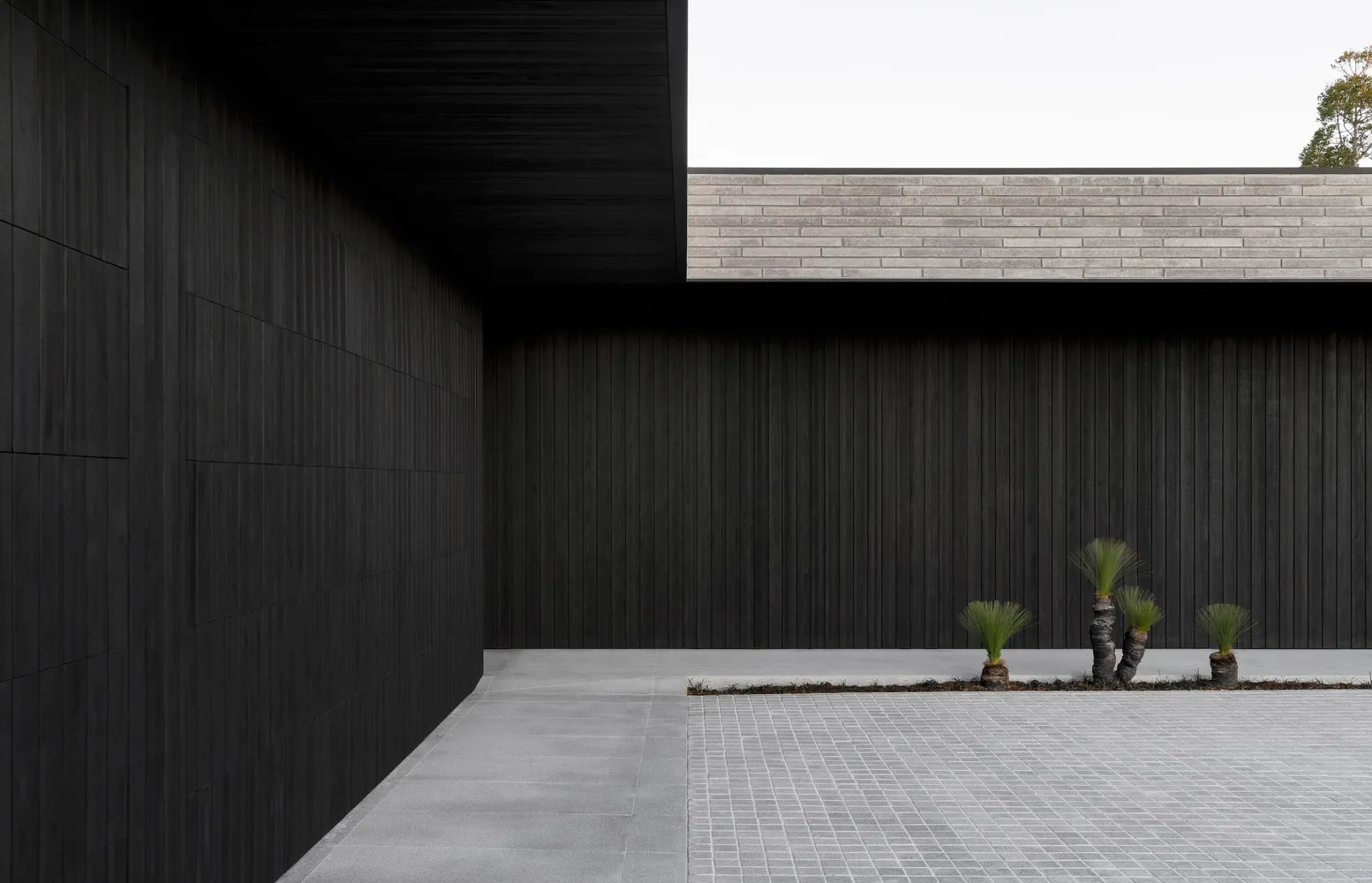 Modern building exterior with black concrete walls and a gray tiled floor.