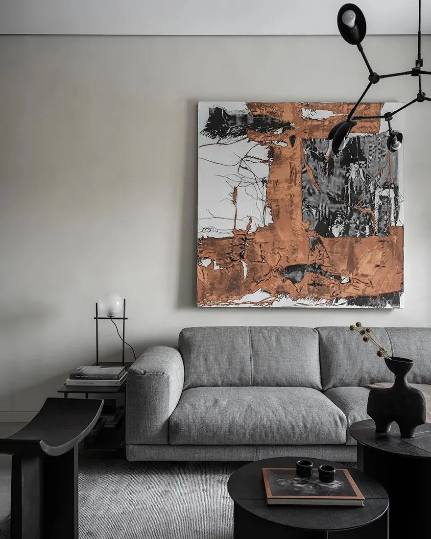 Modern grey living room featuring a contemporary abstract painting and a sleek grey sofa.