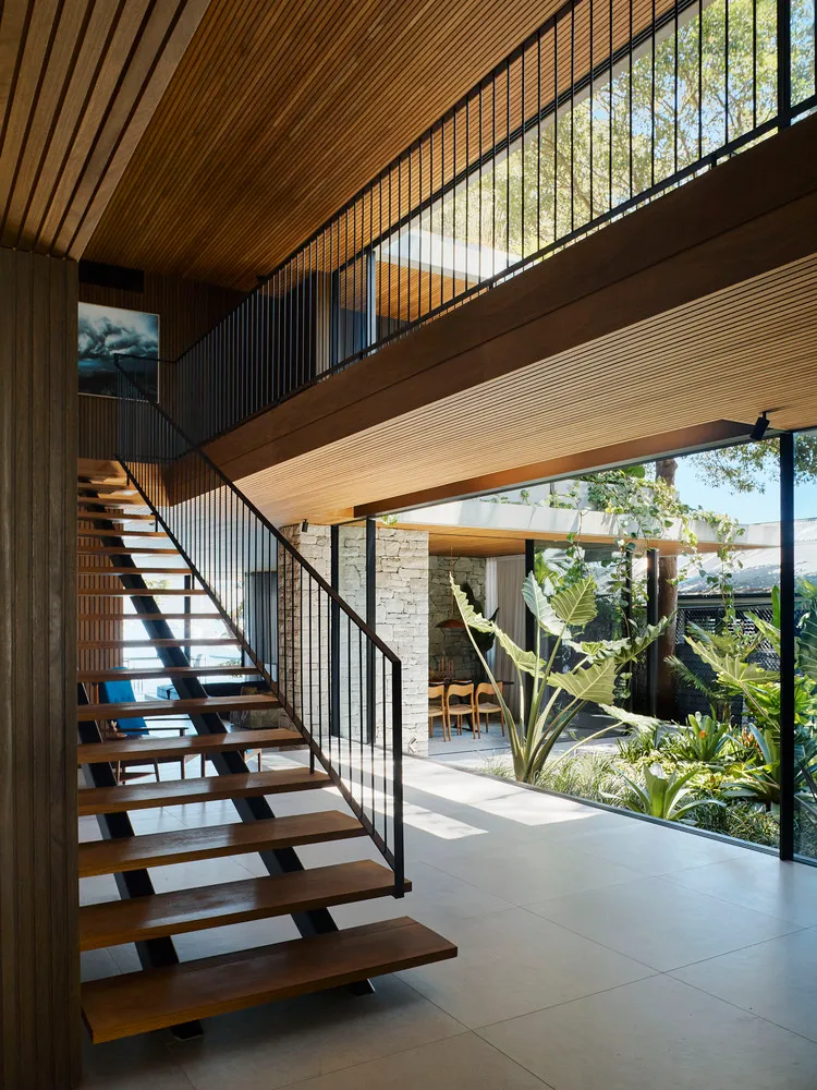 Modern interior space with wooden stairs and large glass windows.