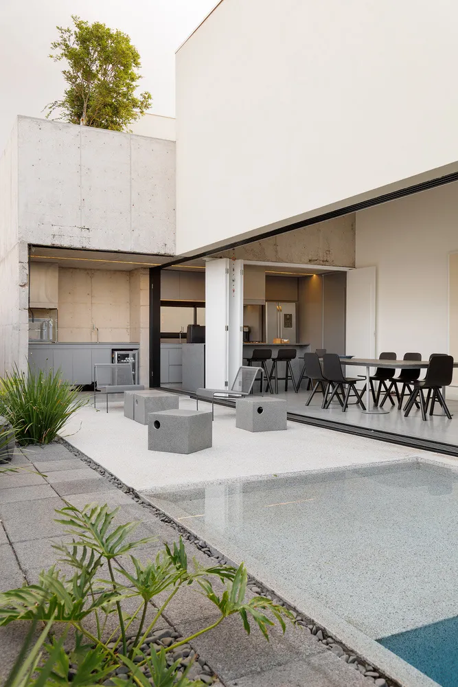 Modern outdoor residential area with concrete flooring, swimming pool, and kitchen area