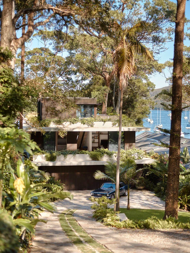 Modern waterfront home with stone, concrete, and glass exterior materials.