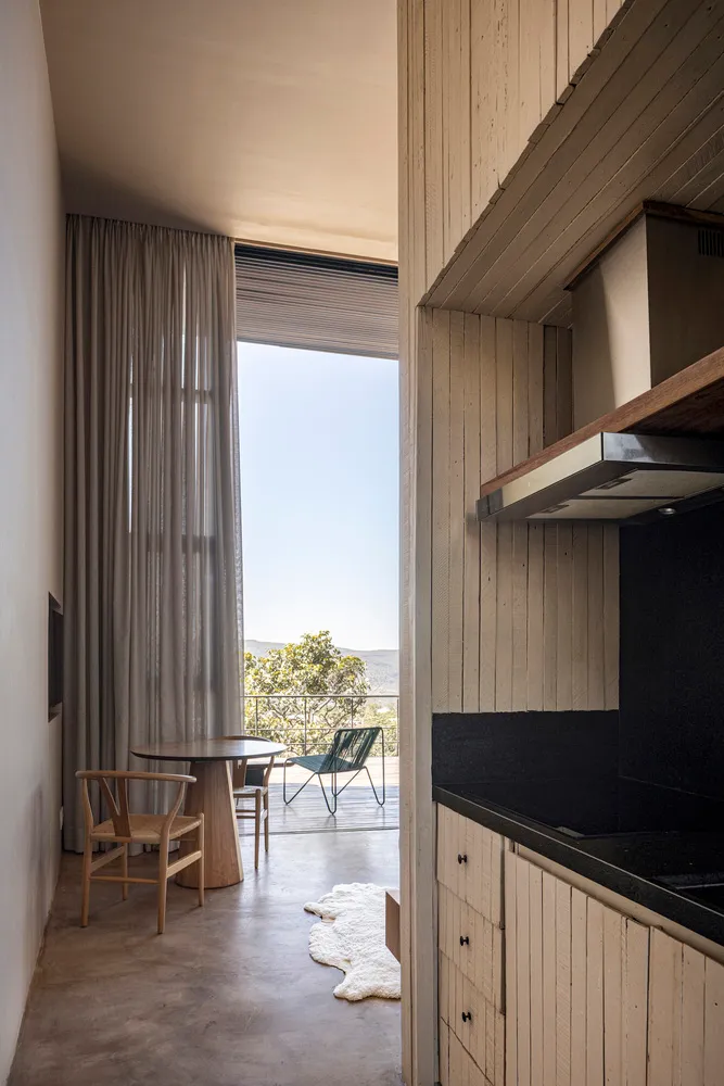 A minimalist residential kitchen featuring wood elements and a view of the outdoors through sheer curtains.